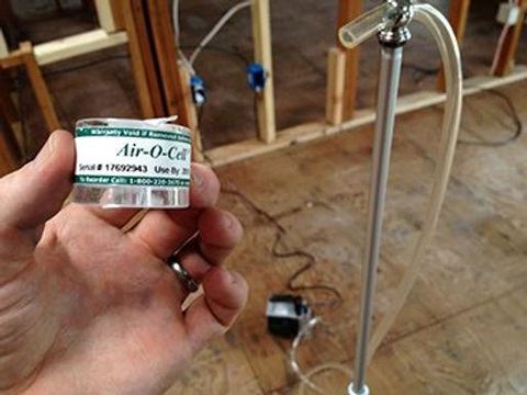 Main tenant une cassette Air-O-Cell, avec un dispositif de prélèvement en arrière-plan