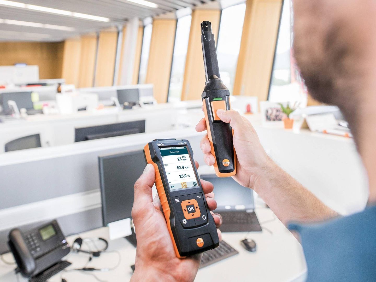 Homme mesurant la ventilation d’un bureau avec un appareil Testo 440 et sa sonde